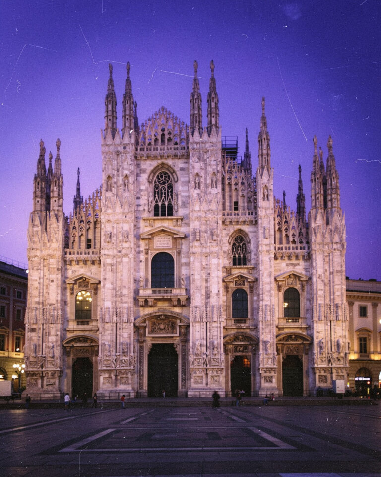 duomo milan dusk photography: Spires of the Duomo di Milano against a violet dusk sky, white marble facade glowing under floo
